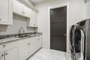 A Laundry Room Built for Everyday Efficiency – Generous cabinetry, a utility sink, extensive counter space, and room for full-size appliances create a practical workspace for washing, folding, storage, and household organization.