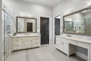 Dual Vanities with Individual Storage – Separate quartz-topped vanities provide each side of the primary bath with dedicated drawer and cabinet space, while oversized mirrors and decorative lighting keep the room bright and functional.