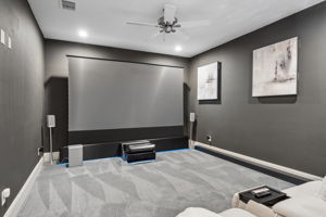 An Entertainment Space with Room to Settle In – The elongated media room provides generous seating distance from the screen, recessed lighting, and space for a refreshment station.