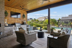 Outdoor Living Designed for All-Day Use – The expansive covered terrace offers generous seating, ceiling fans, a cedar ceiling, an outdoor kitchen, and a clear view of the pool and landscaped backyard.