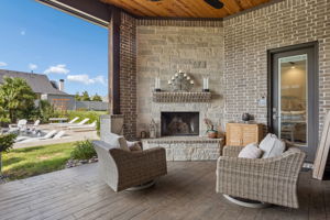 A Fireside Retreat Just Steps from the Pool – The outdoor stone fireplace creates a warm focal point for cooler evenings, while the covered setting keeps the space comfortable and connected to the rest of the backyard.