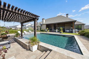 An Outdoor Setting That Feels Complete – From the covered terrace and outdoor kitchen to the pool, pergola, and layered landscaping, every part of the backyard is designed to be used and enjoyed.