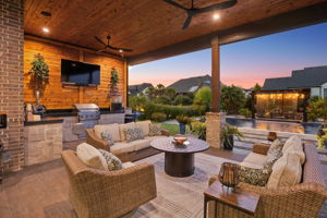 Outdoor Living That Shines After Dark – The covered terrace becomes an evening gathering space with warm lighting, an outdoor kitchen, views of the illuminated pergola, and easy access to the pool.