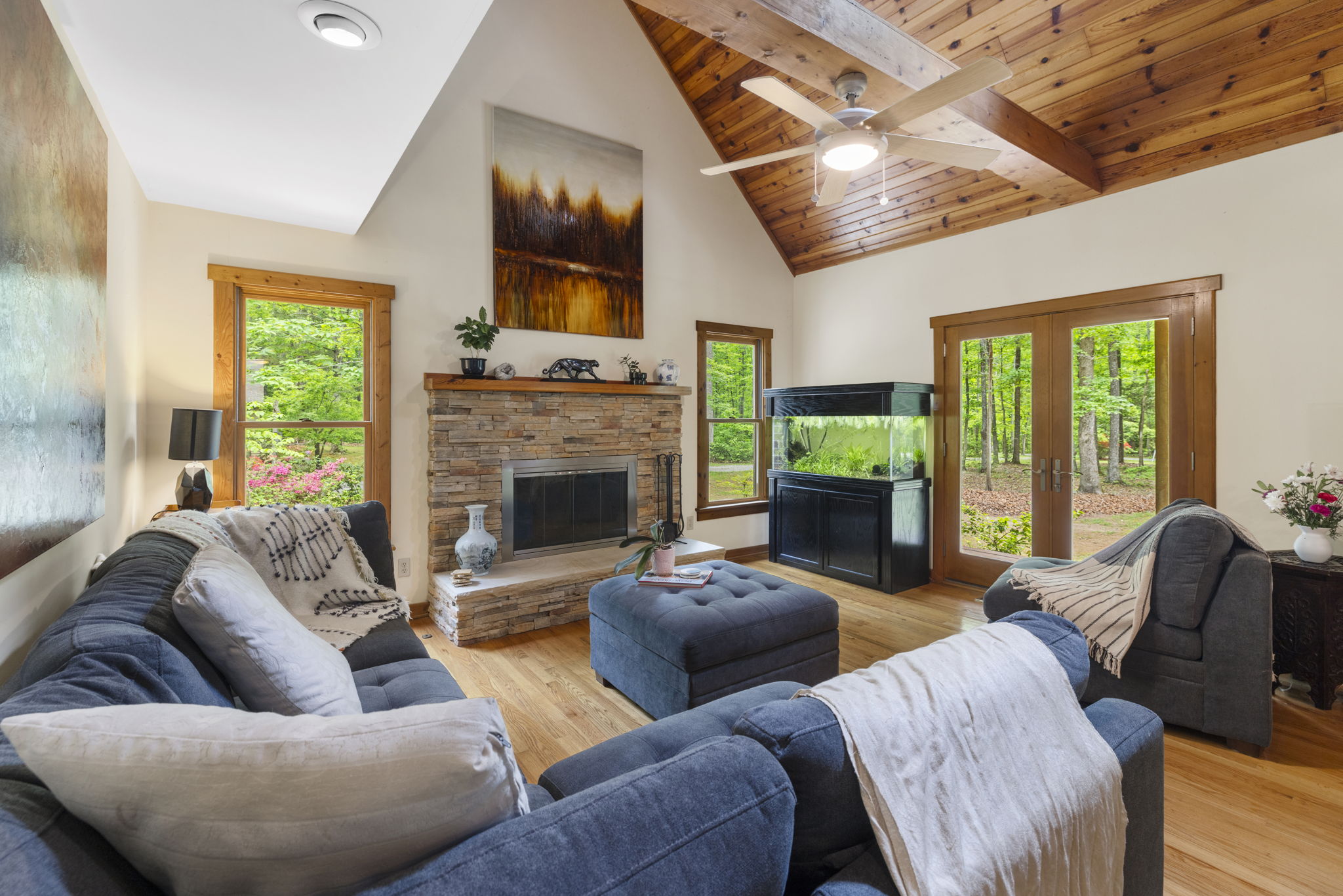 Living room portion of the Great Room with wood floors and a wood burning fireplace.