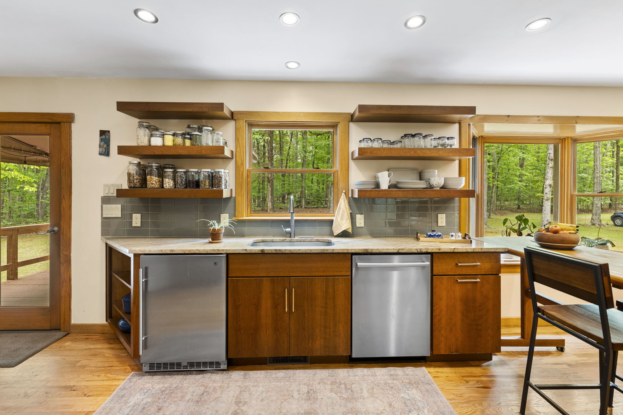 Renovated kitchen in 2016 with tile backsplash, open shelf storage, & granite counters.