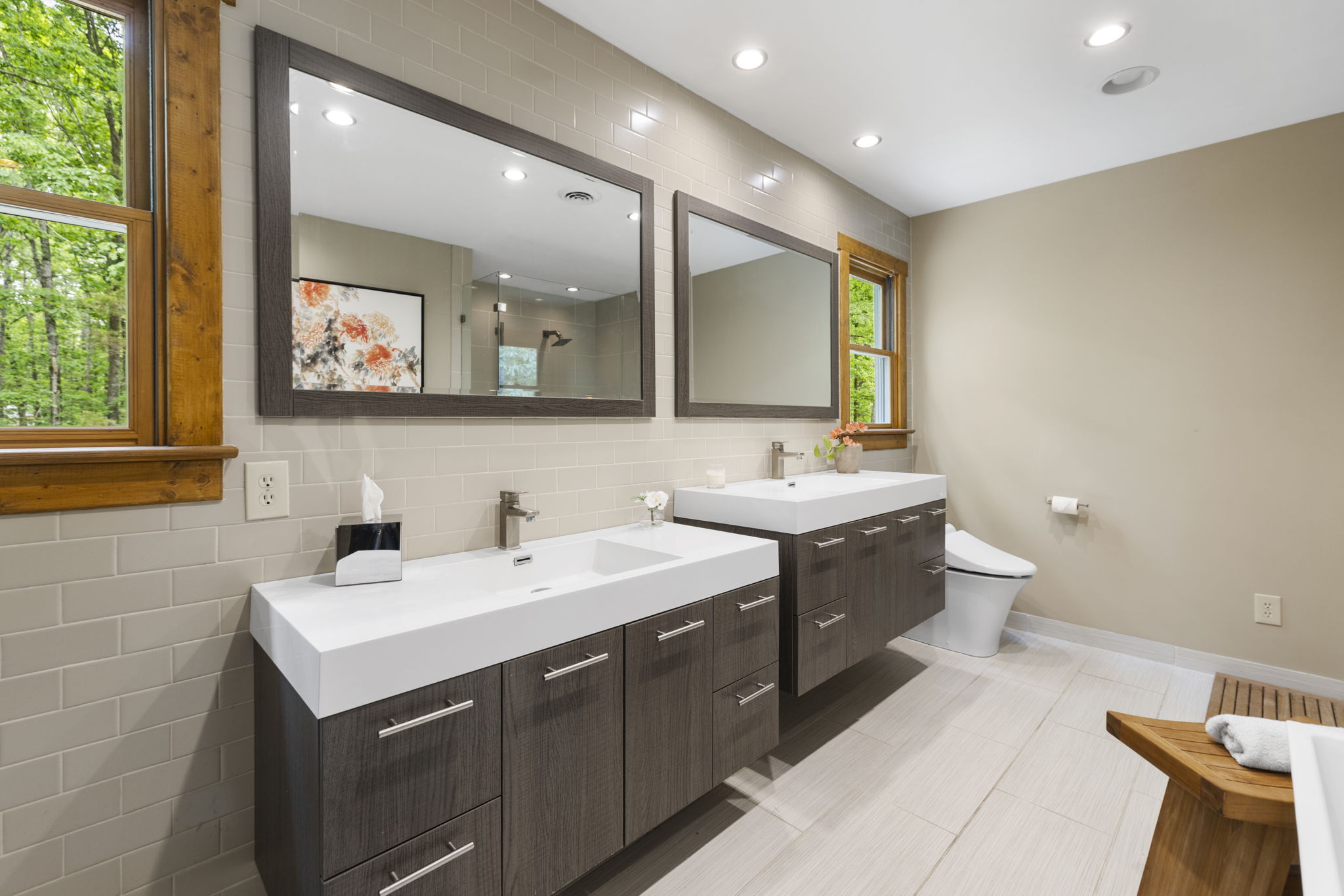 Primary bathroom with dual sink vanities, ceramic tile floors, & recessed can lighting.