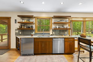 Renovated kitchen in 2016 with tile backsplash, open shelf storage, & granite counters.
