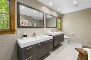 Primary bathroom with dual sink vanities, ceramic tile floors, & recessed can lighting.