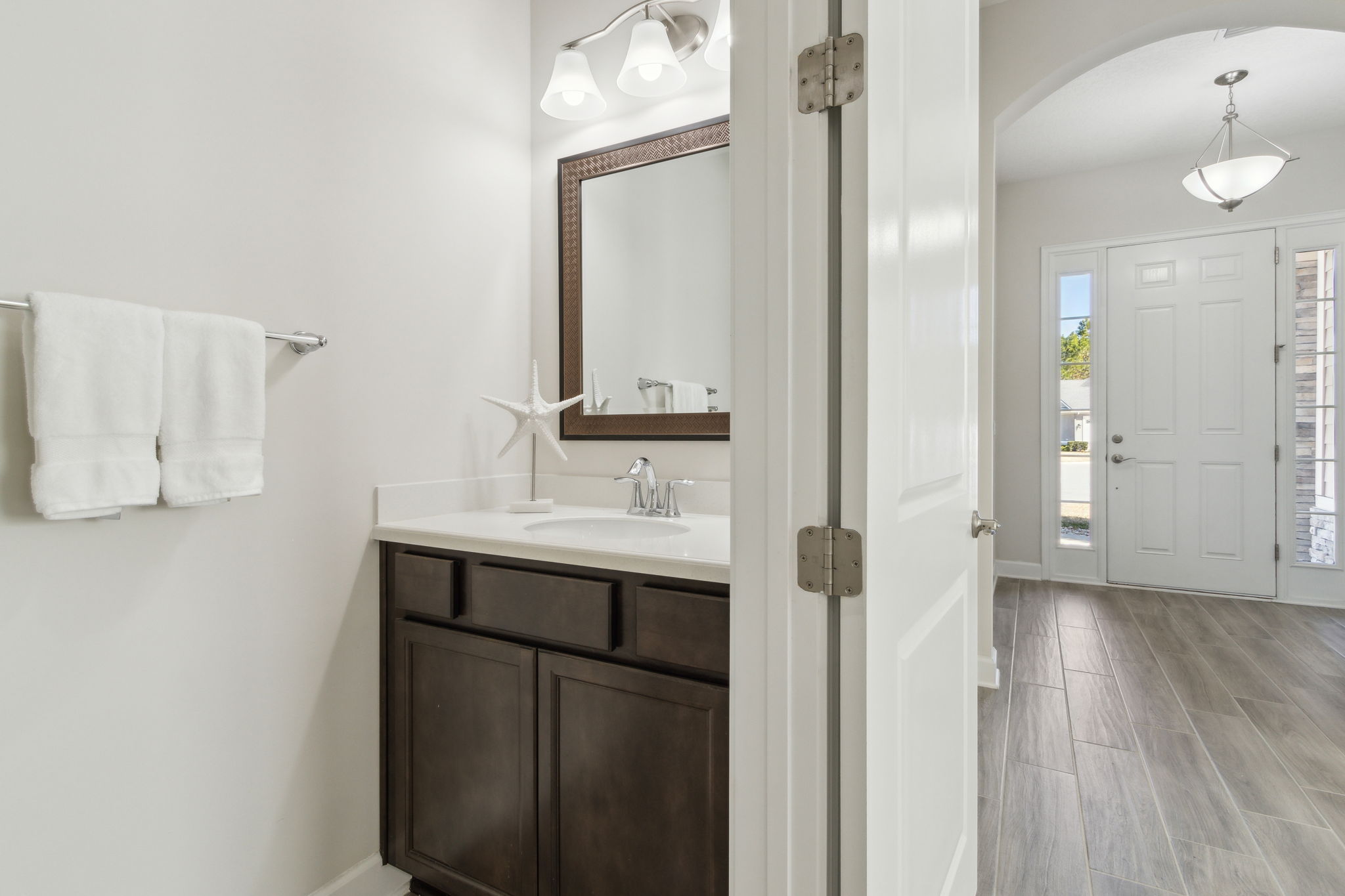 The half bath, with upgraded mirror and lighting,  is conveniently located for guest access.