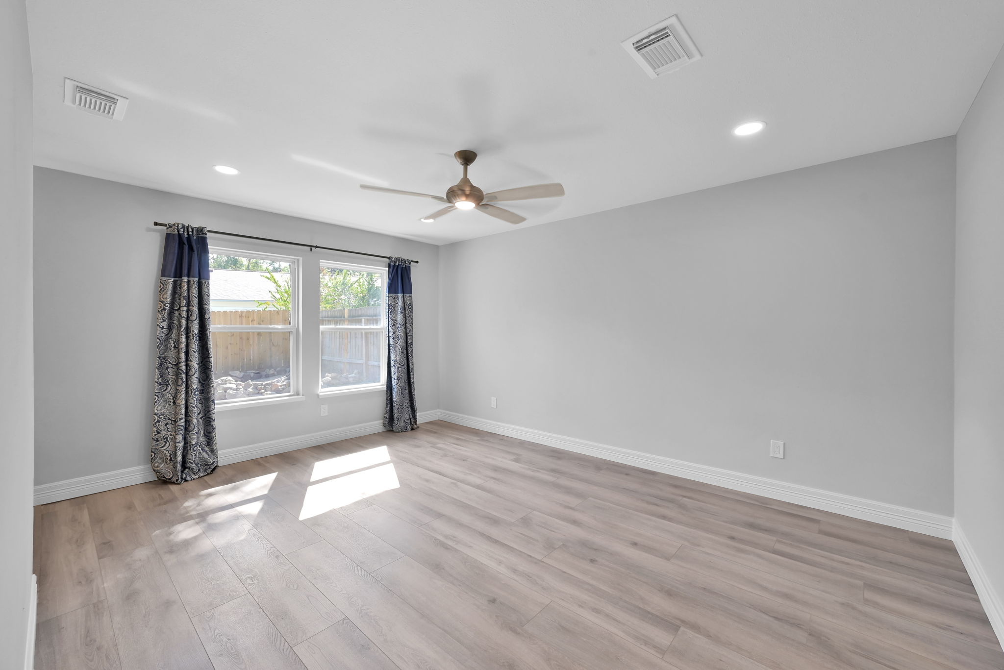 The PRIMARY BEDROOM sits at the end of the hallway (View upon entry). Looks out to the backyard.