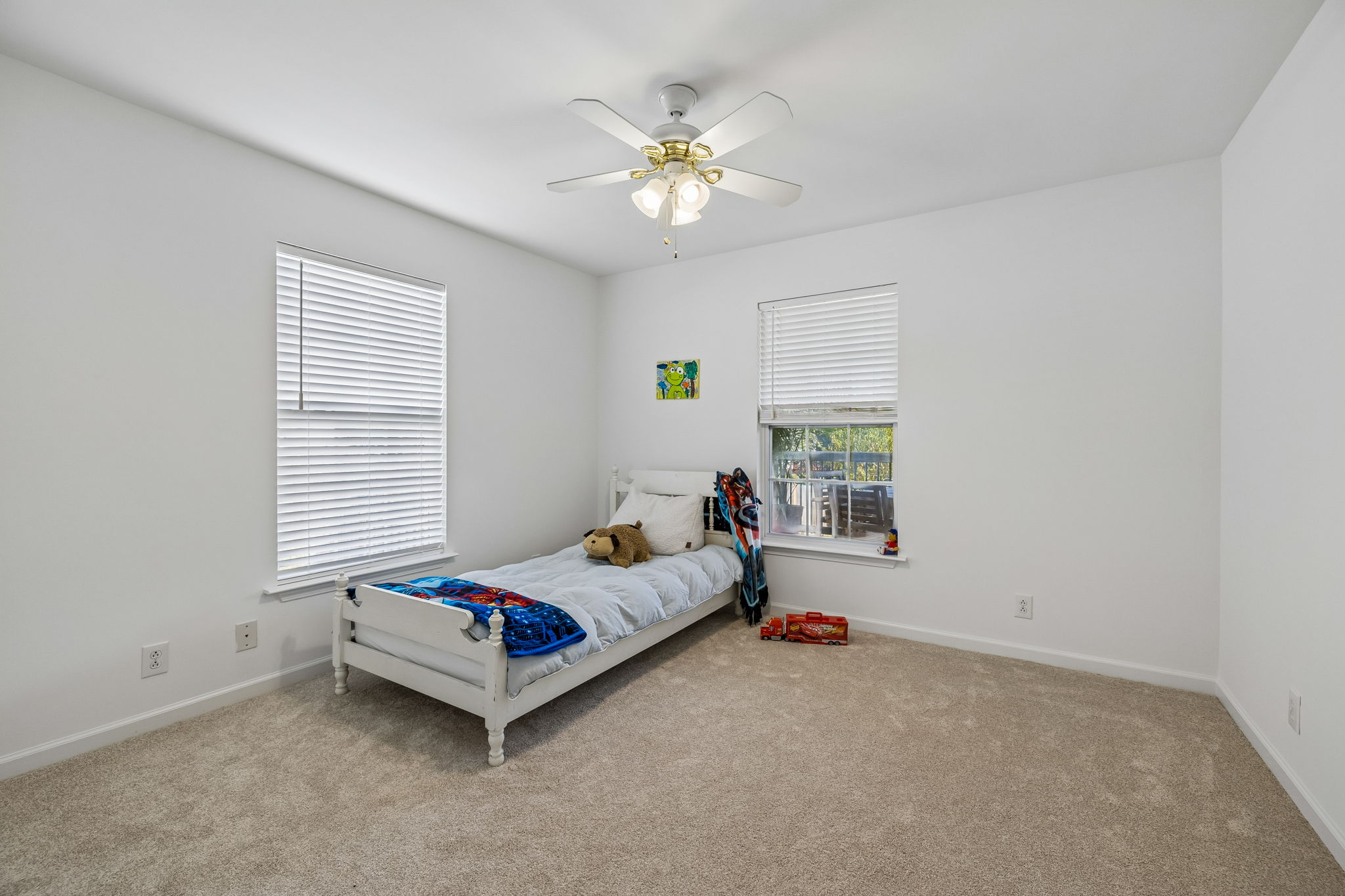 Zoned main floor secondary bedroom with ceiling fan, new carpet/pad, view to covered back deck and yard.