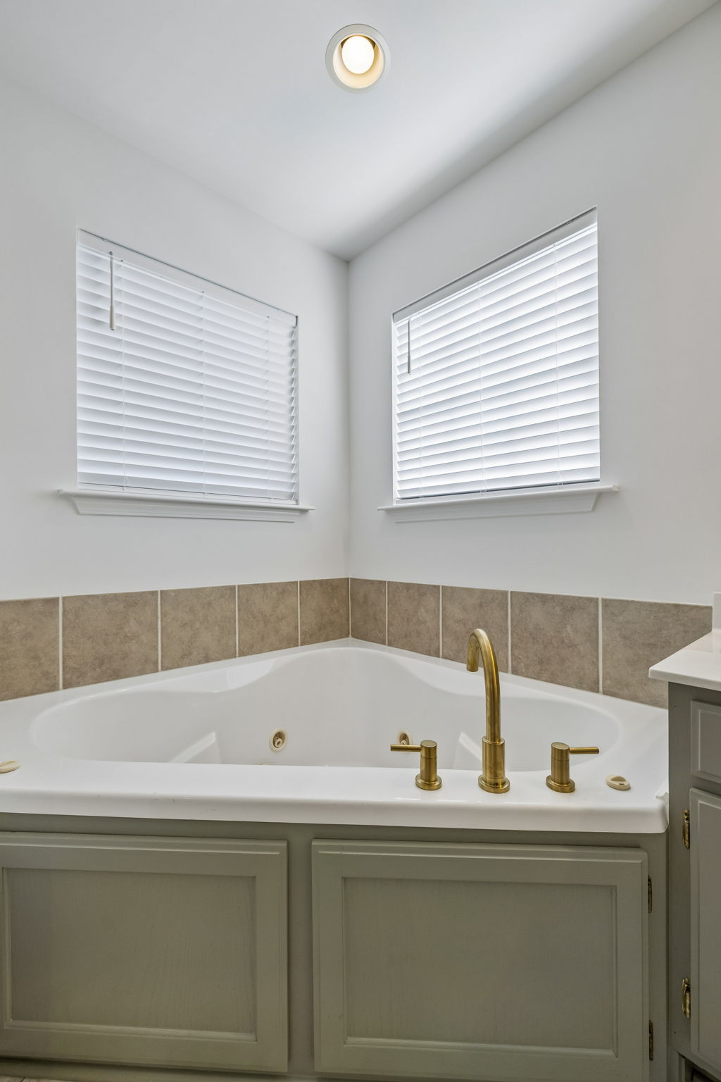 Wonderful Jacuzzi tub with tile surround, east facing windows, and new brushed gold fixtures,.
