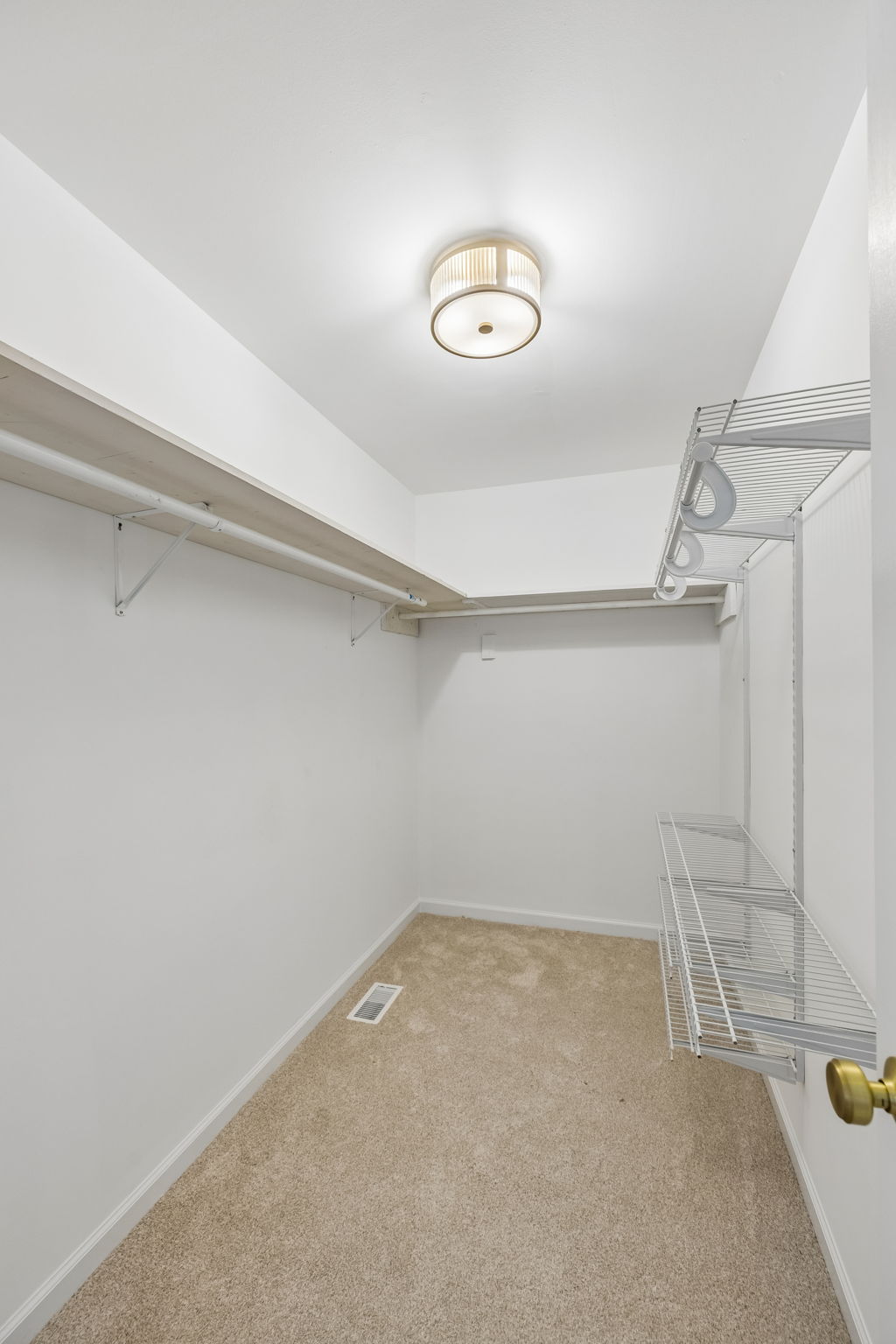Spacious owner's suite walk in closet with extra shelving, new brushed gold light, new carpet/pad.