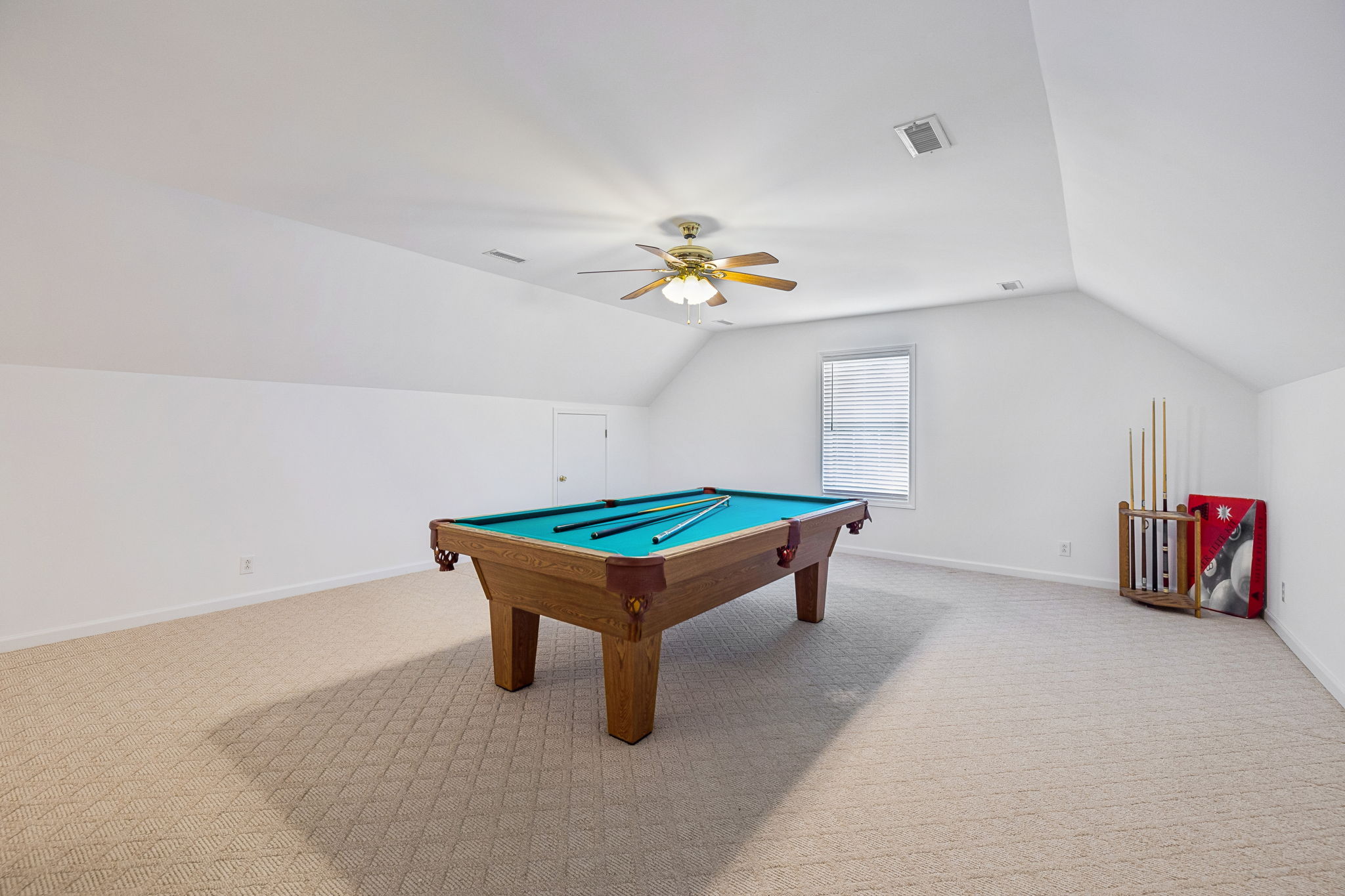 View coming from stairs to very large bonus room, ceiling fan, Berber carpet, and half bath.
