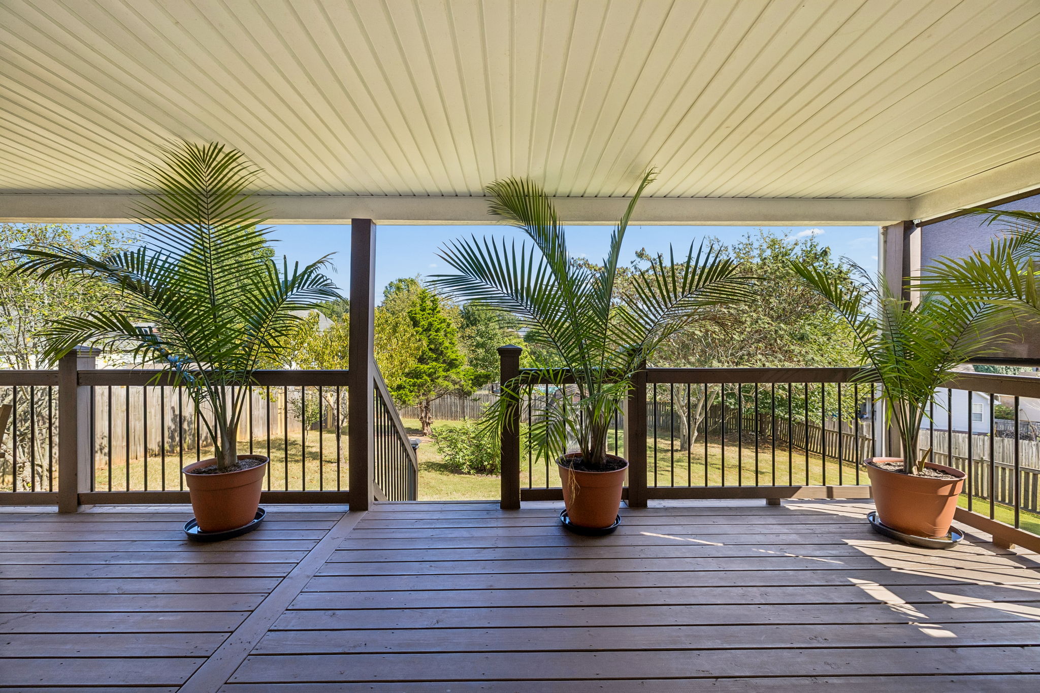 View from kitchen French doors onto the spacious covered back patio overlooking the one third acre fenced back yard with mature trees.