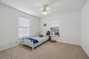 Zoned main floor secondary bedroom with ceiling fan, new carpet/pad, view to covered back deck and yard.