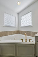 Wonderful Jacuzzi tub with tile surround, east facing windows, and new brushed gold fixtures,.