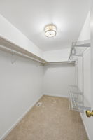 Spacious owner's suite walk in closet with extra shelving, new brushed gold light, new carpet/pad.