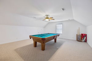 View coming from stairs to very large bonus room, ceiling fan, Berber carpet, and half bath.