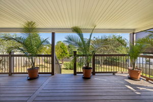 View from kitchen French doors onto the spacious covered back patio overlooking the one third acre fenced back yard with mature trees.