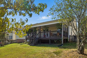 View of covered back deck from spacious one third acre, fenced in back yard with mature trees.