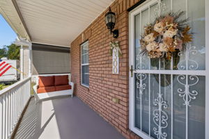 Spacious covered front porch, wrought iron storm door, new concrete sealant, solar sun/privacy shade from West sun..