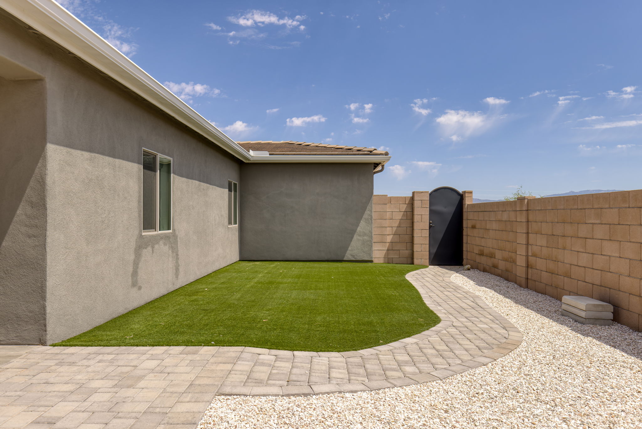 Artificial turf on east side , paver walkway to metal door
