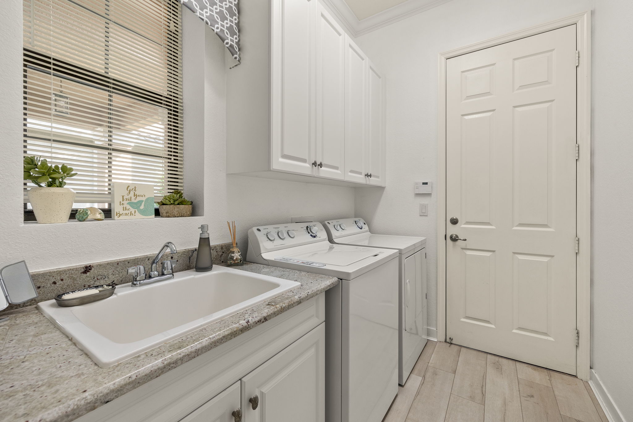 Cabinets, laundry sink, beautiful plank flooring and crown molding make this laundry room a winner!  Just beyond the Laundry room door is the 2 car garage with extra insulation in the garage door and attic. Exterior surveillance cameras. Wiring for portable generator present.
