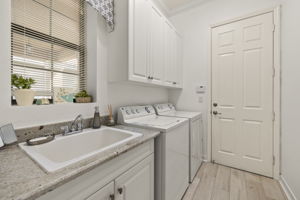 Cabinets, laundry sink, beautiful plank flooring and crown molding make this laundry room a winner!  Just beyond the Laundry room door is the 2 car garage with extra insulation in the garage door and attic. Exterior surveillance cameras. Wiring for portable generator present.