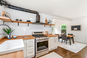 This kitchen is all about warmth and character, with butcher block countertops, a white subway tile backsplash that reaches the ceiling, and a large farm sink ready for whatever you need. Live edge shelves add a natural touch, offering the perfect spot to showcase your favorite finds while keeping things light and open.