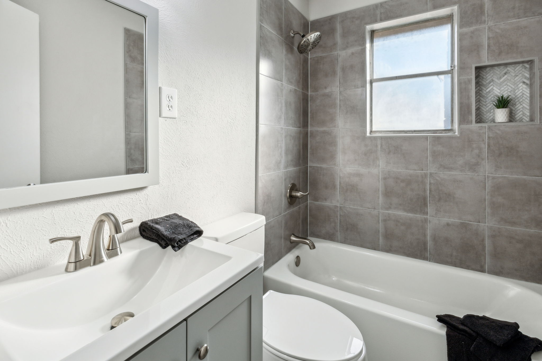 Wow! This TOTALLY updated Guest Bath is STunning!  NEW tile, NEW Tub with Herringbone inset, NEW cabinetry, New Faucets and Shower Head, NEW Mirror, Lights and Toilet!  Your guests will be so impressed!