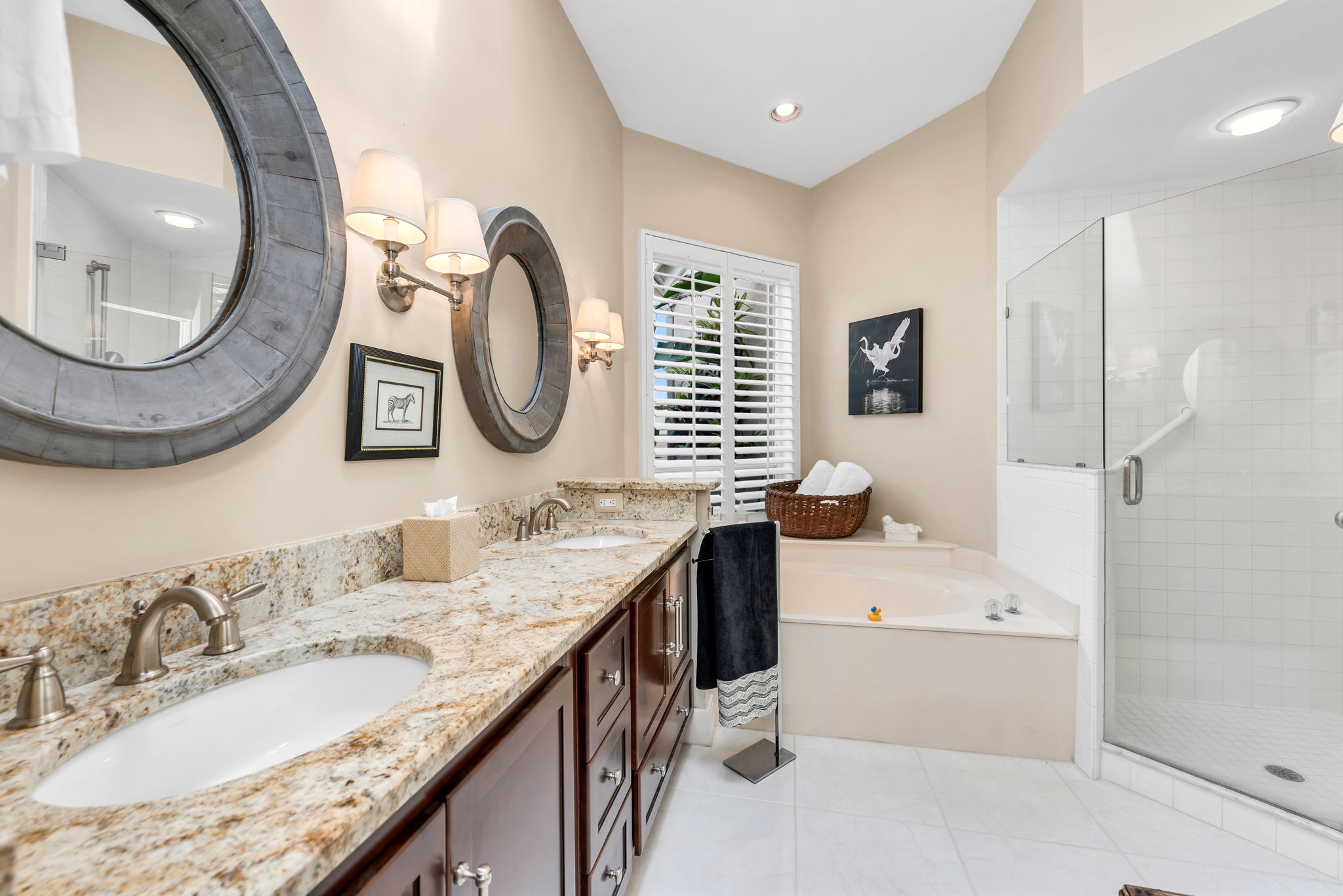 Primary Bathroom has dual sinks, updated granite countertops, cabinetry, seamless glass shower enclosure, and garden tub