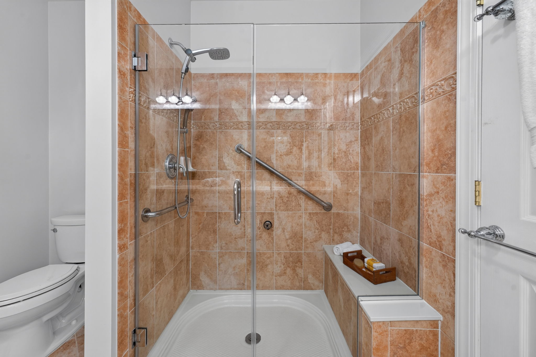 The private bath is freshly painted and features a double-sink vanity with makeup counter, seated shower with frameless shower door, and ceramic tile flooring.