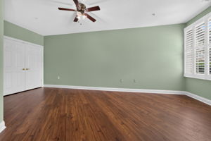 The second bedroom features a ceiling fan, 3 door closets + utility closet, plantation shutters, and LVT flooring.