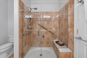 The private bath is freshly painted and features a double-sink vanity with makeup counter, seated shower with frameless shower door, and ceramic tile flooring.