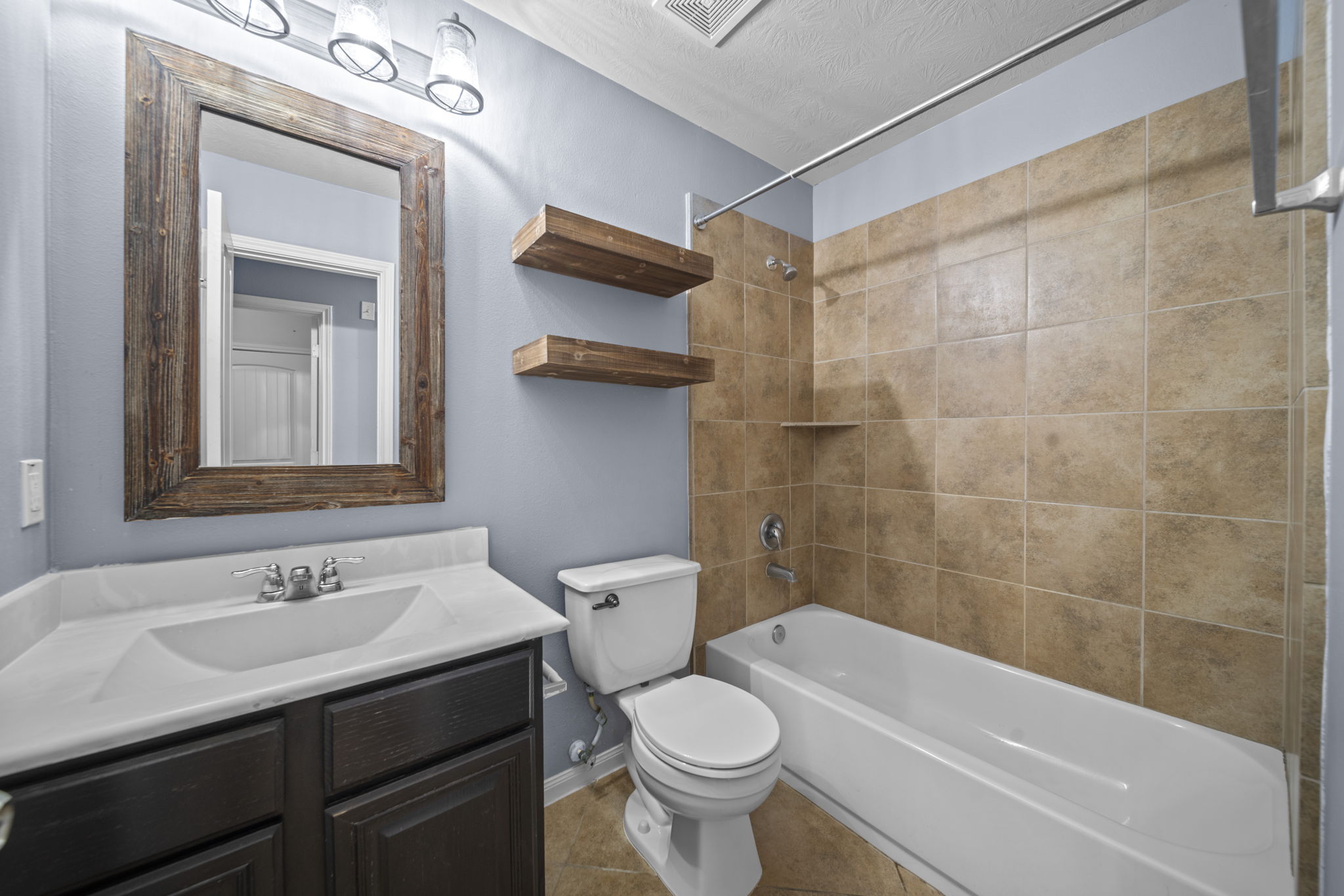 Full bathroom with tile, a shower/tub combo and an updated vanity with cultured marble countertops.