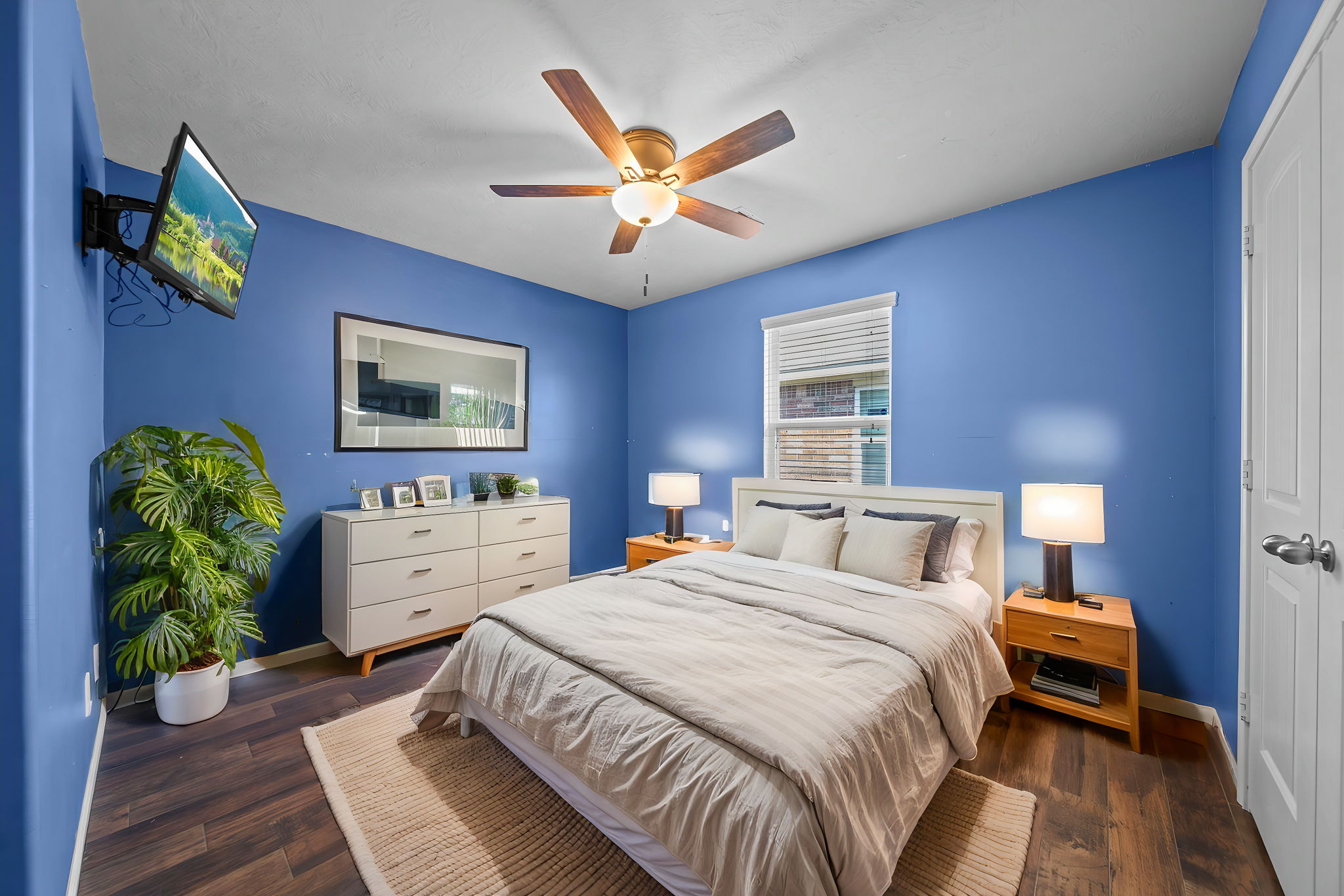 Secondary bedroom with wood-look tile flooring, a ceiling fan & 2" blinds.