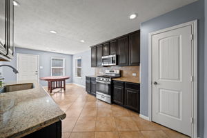 Kitchen with updated stainless steel appliances (2024) granite countertops, recessed lighting, tile flooring and a walk-in pantry!