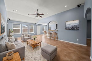 Spacious living area with tile flooring, recessed lighting, surround sound, a ceiling fan, 2" blinds, & arched entryways!