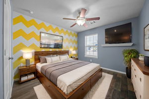 Secondary bedroom with wood-look tile flooring, a ceiling fan, & 2" blinds.