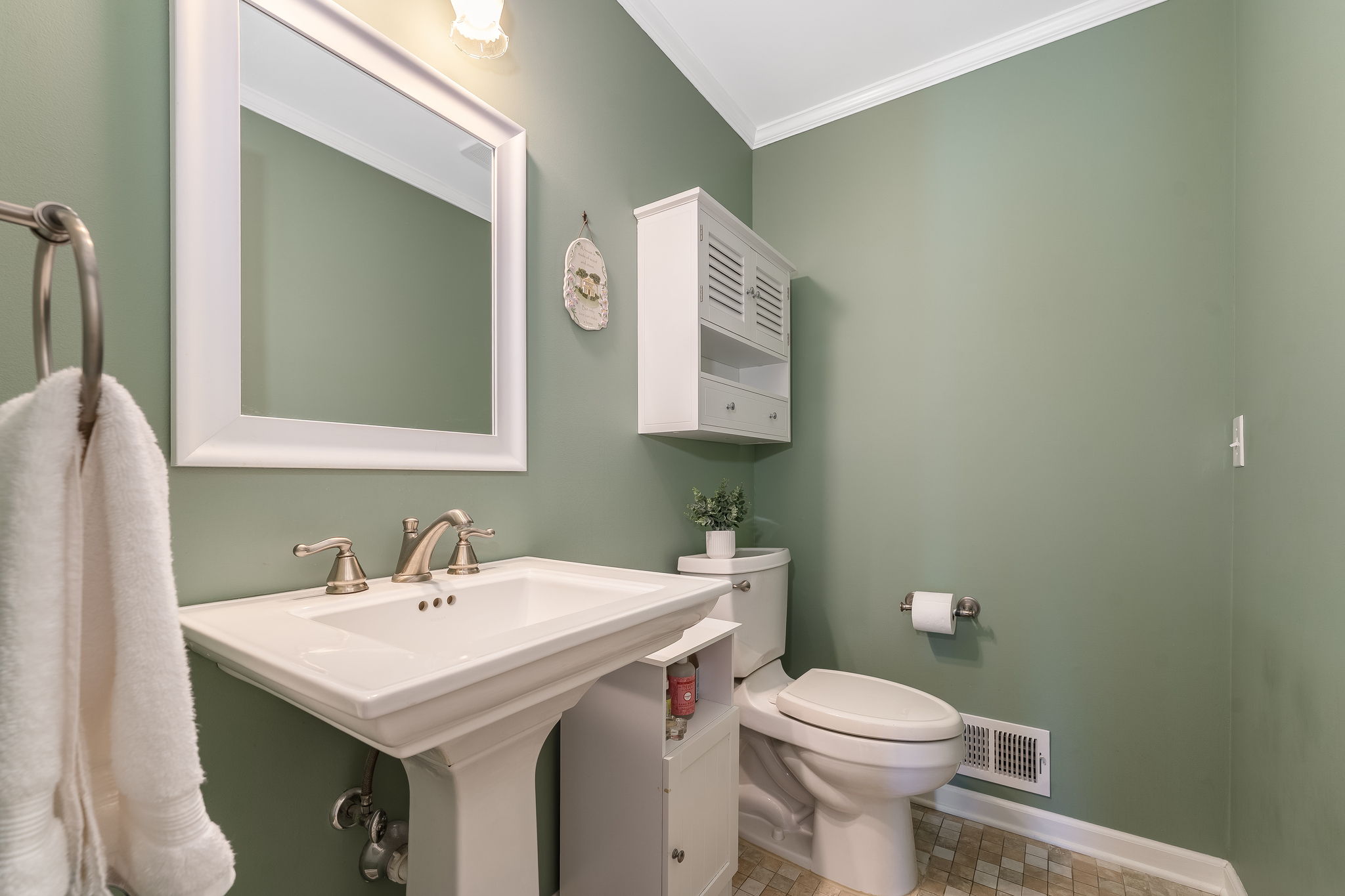 Crown moulding, framed mirror, wall cabinet, pedestal sink, ceramic tile floor.