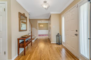 Entry door with sidelites, crown moulding, double door closet, turned staircase, hardwood floor.