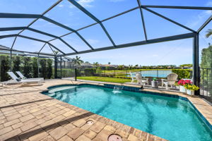 Swimming Pool with Sitting Area.  Featuring a Fenced In Backyard with Fire Pit and Lake View.