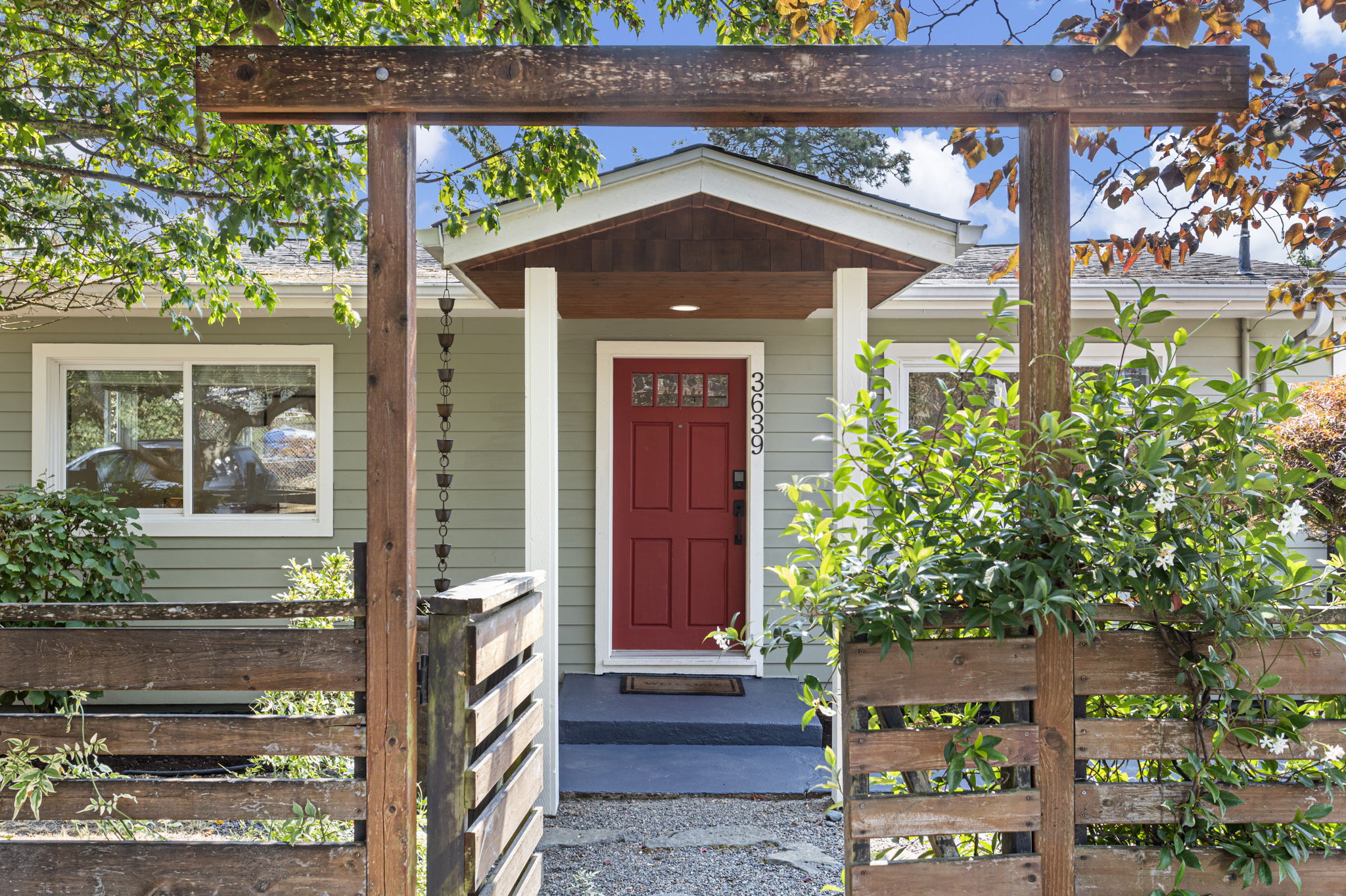 Some houses earn the straight-on shot. Here, the jasmine arbor, gate and red door line up into a front approach worth framing.