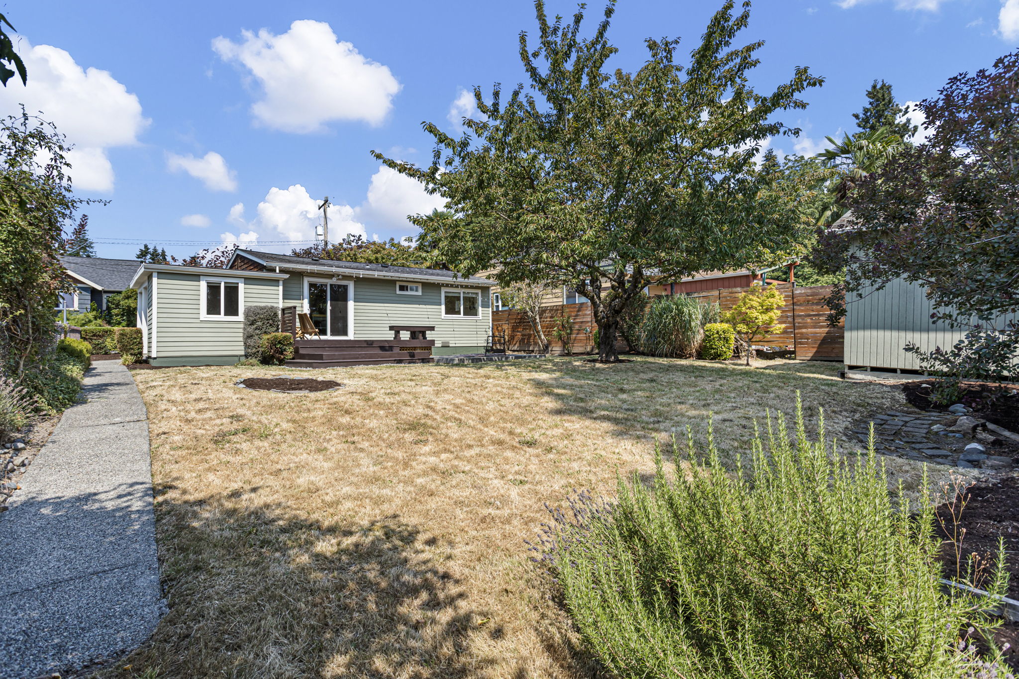 From the far end, the scale finally registers: a broad south-facing yard stretching out from the house and deck, with light lasting into the evening and a vacated alley behind adding extra buffer and privacy.