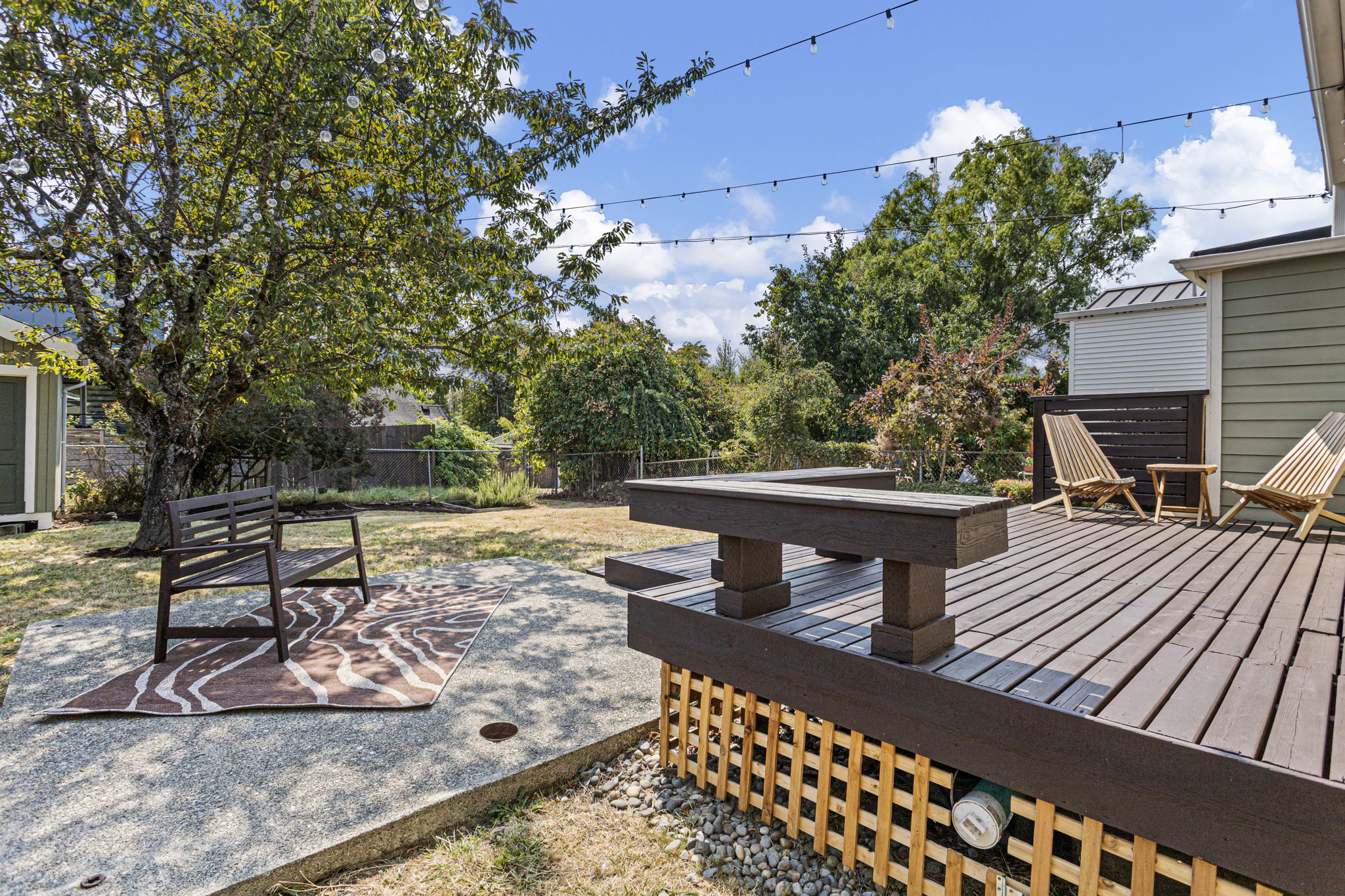Out back, the lot breaks into places to actually use it: deck, separate patio, open yard and a mature tree tying the whole thing together.