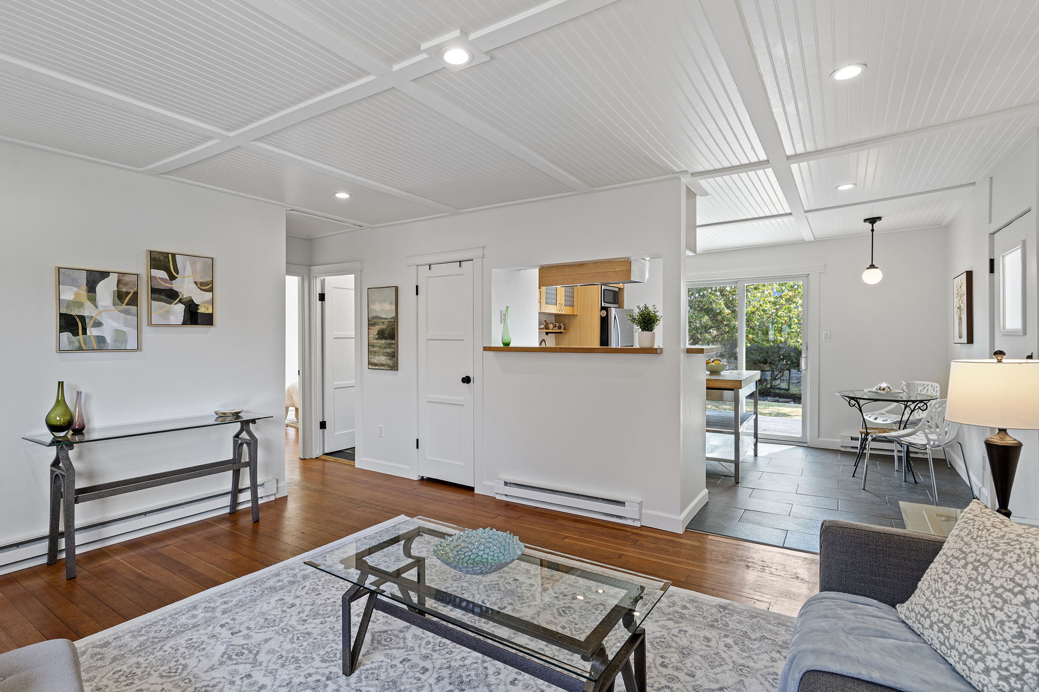 From the living room, the whole plan reads front to back in one glance—kitchen, dining, then deck and backyard beyond.