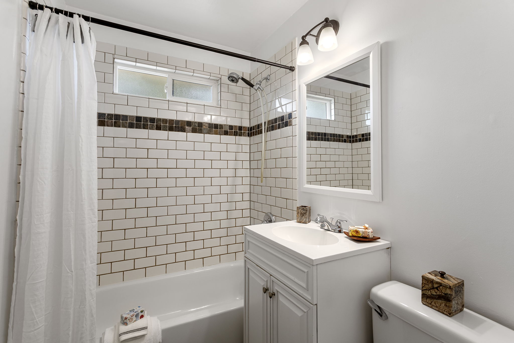 The tub was refinished for launch, with a full subway-tile surround, frosted window for daylight and privacy, and a large linen cabinet just out of frame for towels and bath storage.