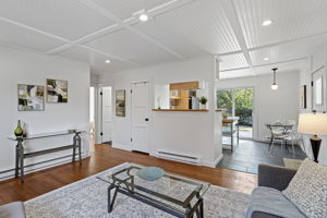 From the living room, the whole plan reads front to back in one glance—kitchen, dining, then deck and backyard beyond.