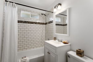 The tub was refinished for launch, with a full subway-tile surround, frosted window for daylight and privacy, and a large linen cabinet just out of frame for towels and bath storage.